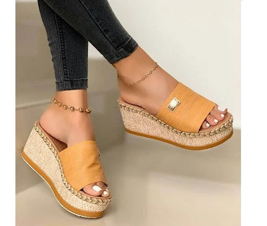 Woman wearing mustard yellow platform wedge sandals with braided jute soles and black skinny jeans