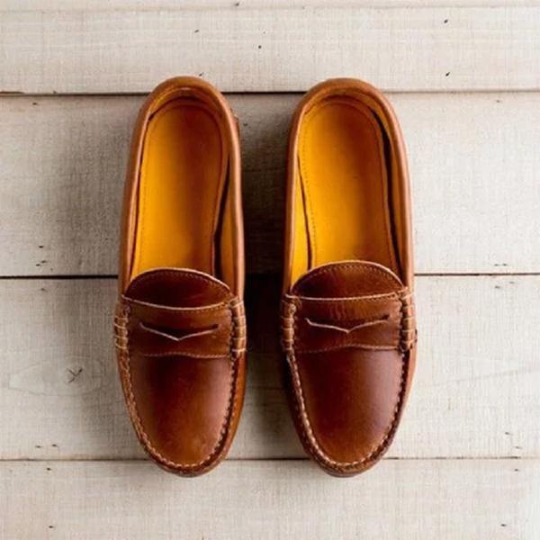 Pair of brown leather moccasin loafers with detailed stitching on wooden background