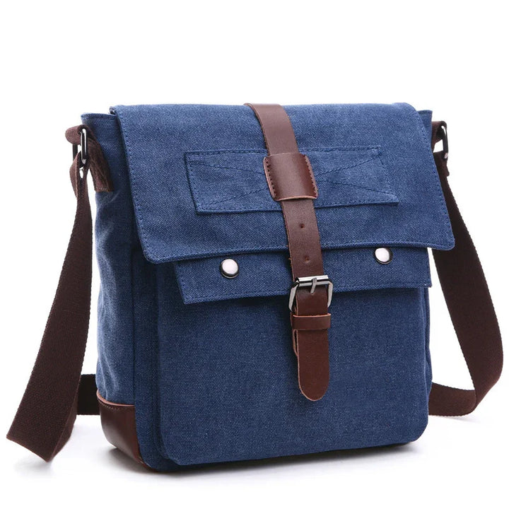 Blue canvas messenger bag with brown leather strap and adjustable shoulder strap