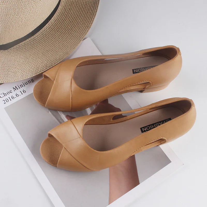 Tan leather peep-toe flats on a magazine page alongside a beige straw hat with black band
