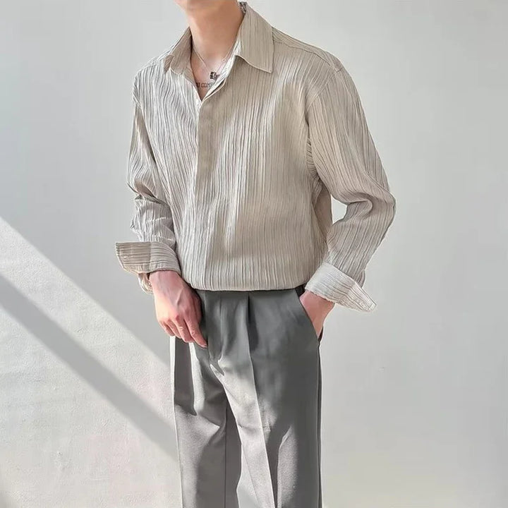 Man wearing beige textured long-sleeve shirt and gray pleated pants in natural light