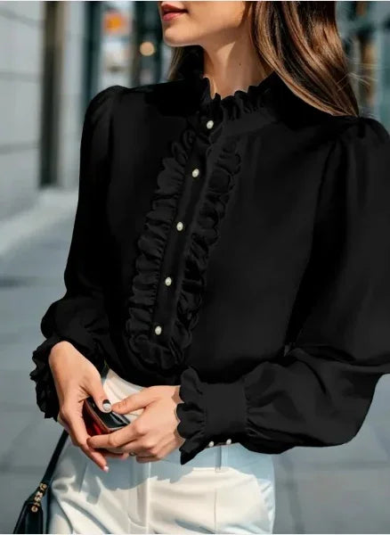 Woman wearing black ruffled blouse with pearl buttons and white pants outdoors