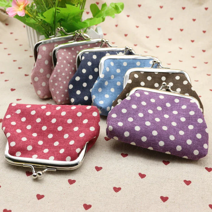 Row of colorful polka dot fabric coin purses with metal clasps on beige cloth with red hearts