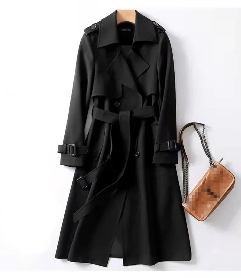 Elegant black trench coat with belt and buckle details hanging next to a brown leather handbag with chain strap