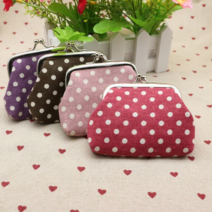 Set of four polka dot fabric coin purses in red, pink, brown, and purple on heart-patterned cloth with green potted flowers