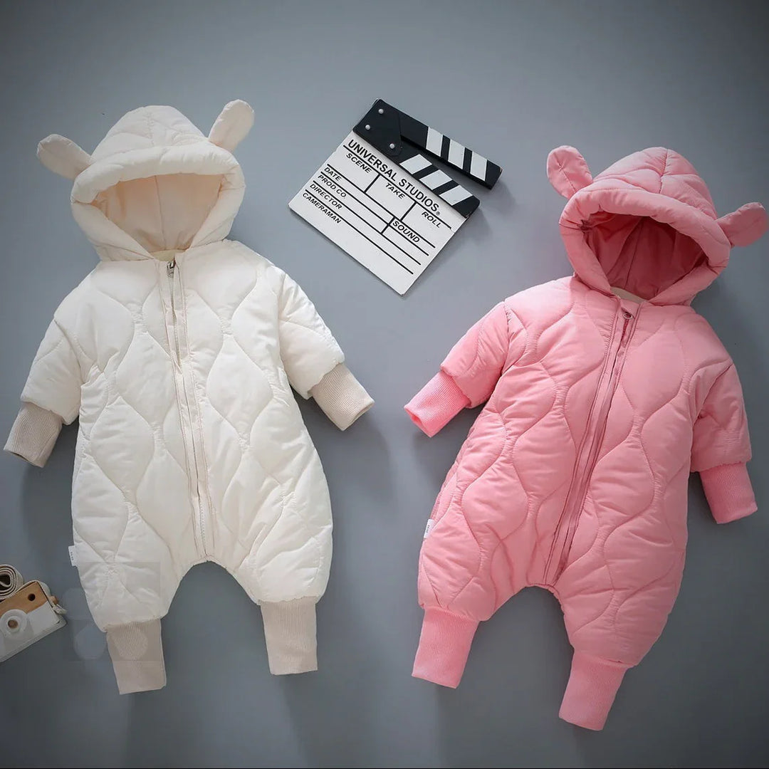 White and pink baby padded jumpsuits with hood and bear ears, on gray background with clapperboard