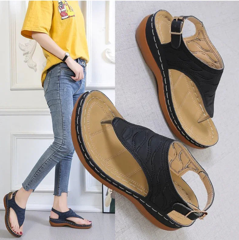 Black wedge sandals with tan stitching and buckled ankle strap, modeled with blue skinny jeans and yellow t-shirt