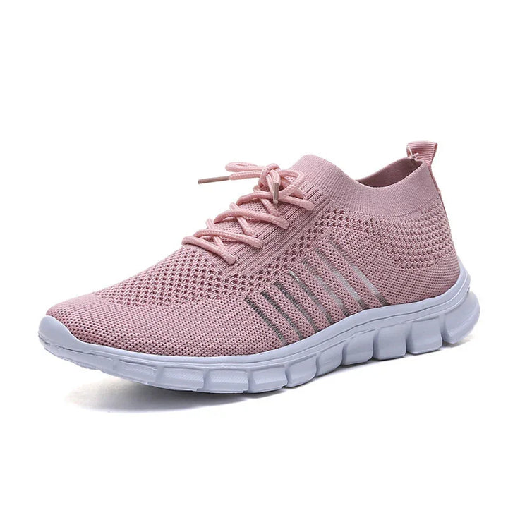 Light pink breathable knit athletic sneaker with white flexible sole and lace-up closure