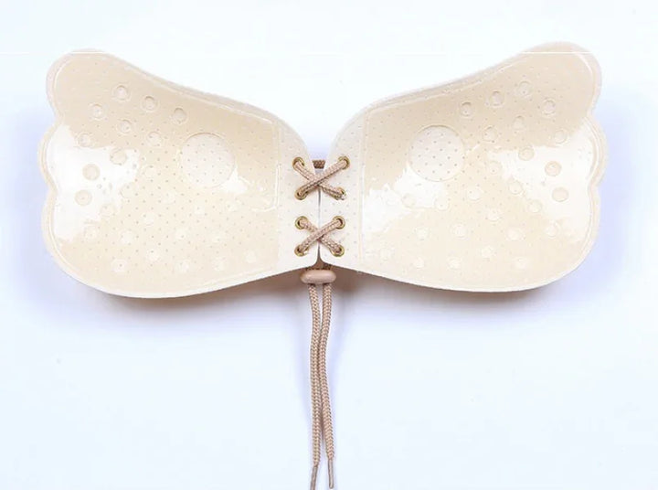 Beige adhesive strapless bra with butterfly-shaped cups and front lace-up closure on white background
