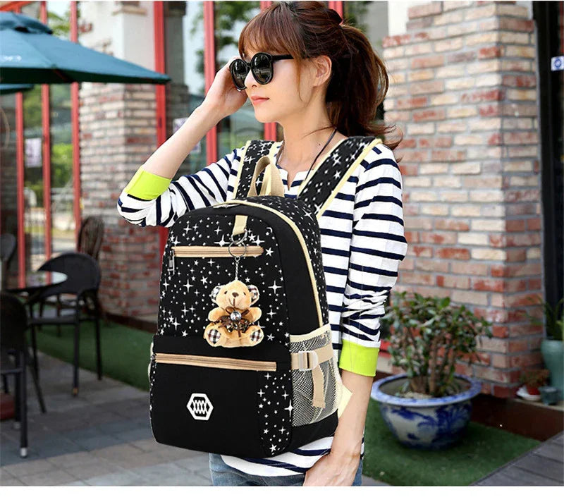 Woman wearing black star-patterned backpack with teddy bear keychain outdoors near brick wall