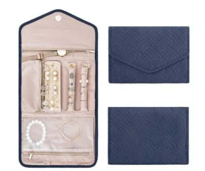 Blue quilted jewelry organizer pouch with beige interior holding pearl bracelet and rings