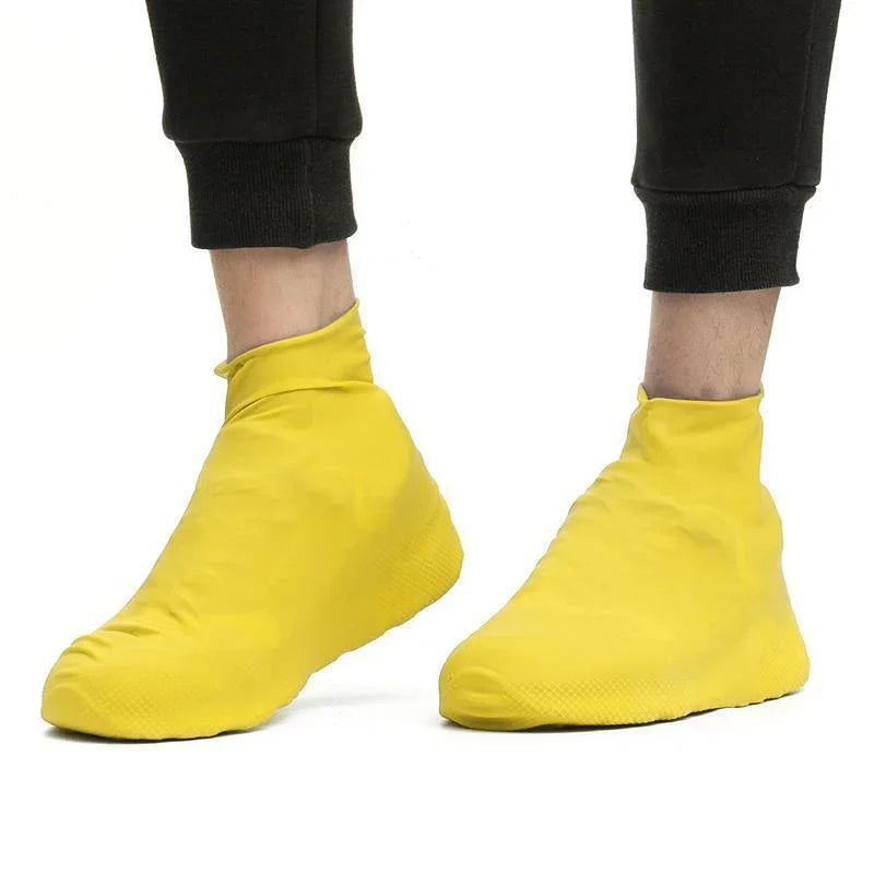 Person wearing vibrant yellow waterproof shoe covers with black pants on white background
