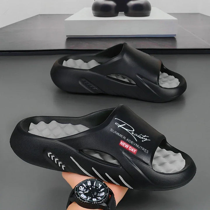 Black slip-on summer sandals with gray wavy insoles and text 'Reality Summer Adventures New Day' on top