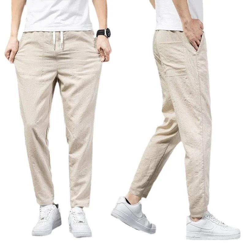 Men's beige casual jogger pants with elastic waist and pockets, paired with white sneakers