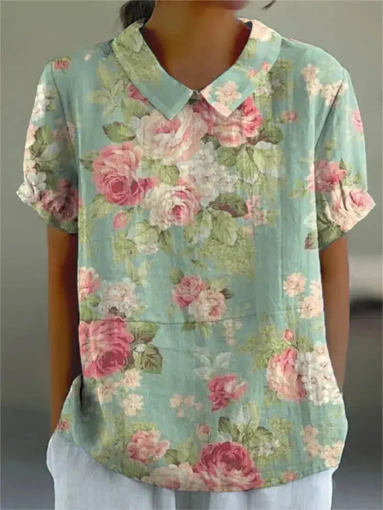 Woman wearing a light blue floral blouse with pink and white roses and a Peter Pan collar