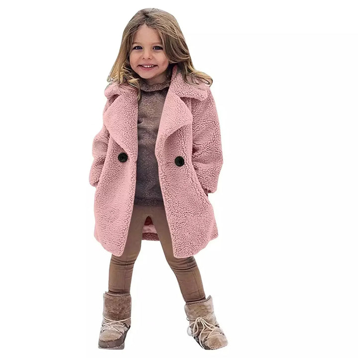 Smiling young girl wearing a pink teddy coat, beige leggings, and fur-lined boots