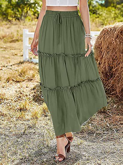 Woman wearing olive green tiered maxi skirt and brown heeled sandals outdoors by hay bale