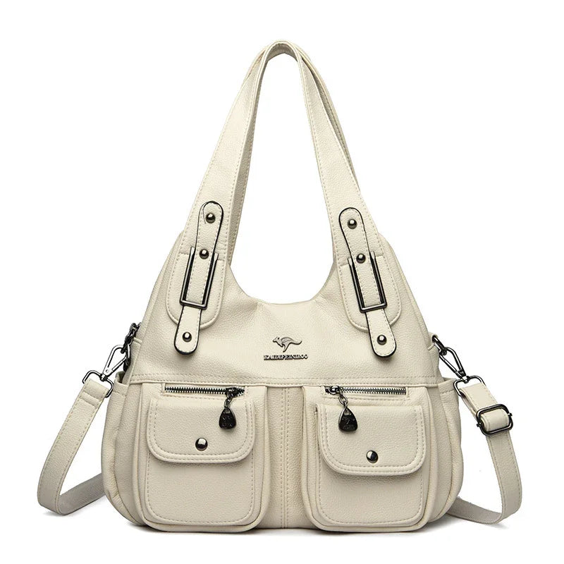 Cream leather handbag with dual top handles, front zipper and snap pockets, adjustable shoulder strap