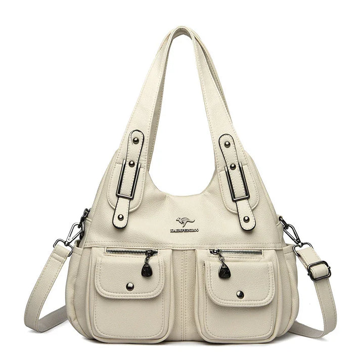 Cream leather handbag with dual top handles, front zipper and snap pockets, adjustable shoulder strap