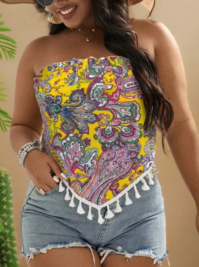 Woman wearing yellow paisley print strapless top with tassels and denim cutoff shorts