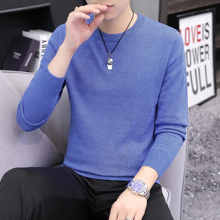 Man wearing a blue crew neck sweater and silver watch sitting on gray couch with framed inspirational text