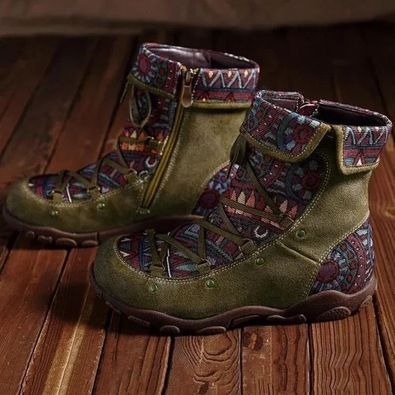 Pair of olive green suede boots with colorful tribal fabric panels and side zippers on wooden floor