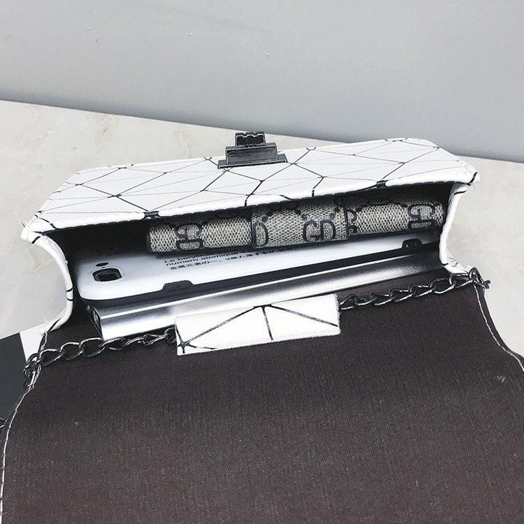 Open white geometric pattern chain purse holding a smartphone and a designer wallet on marble surface