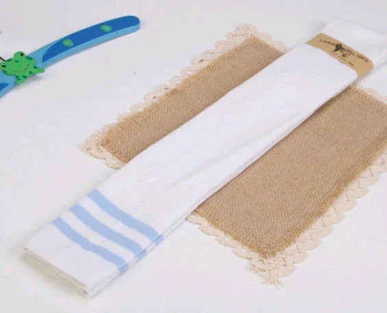 White cotton kitchen towel with blue stripes folded on burlap placemat with lace trim on white surface