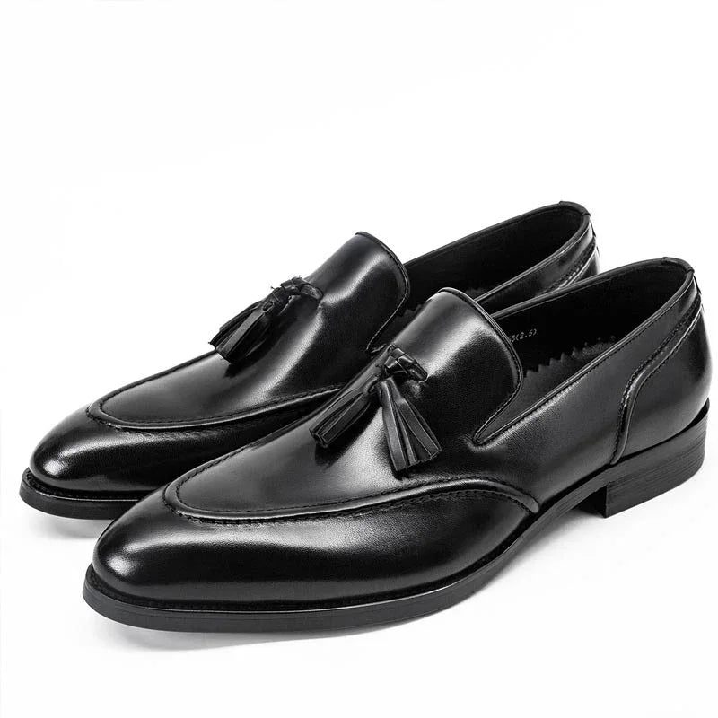Pair of black leather tassel loafers with sleek design and low heels on a white background
