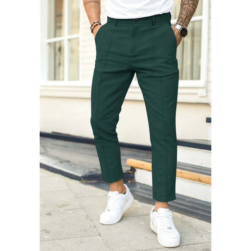 Man wearing dark green slim-fit cropped trousers with white sneakers and a white t-shirt