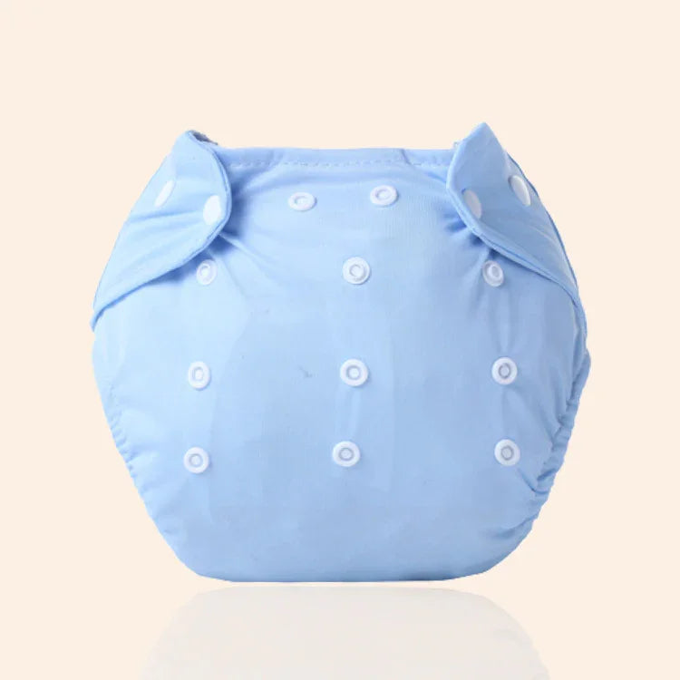 Light blue reusable cloth baby diaper with multiple white snap buttons on a beige background