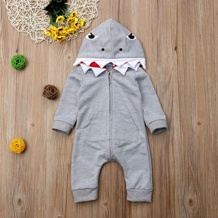 Gray baby romper with shark-face hood and white teeth detail on wooden floor background