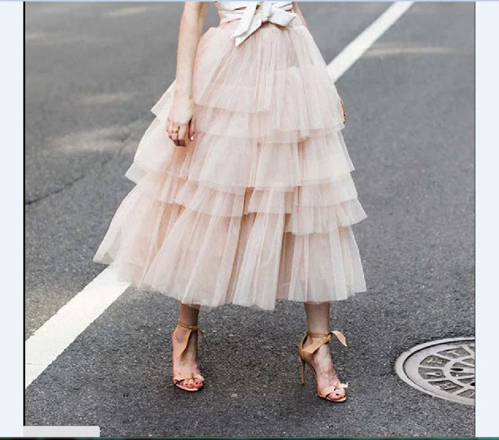 Woman wearing layered pink tulle midi skirt and beige high-heeled sandals on city street