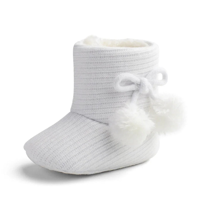White knitted baby bootie with fluffy pom-poms and soft inner lining