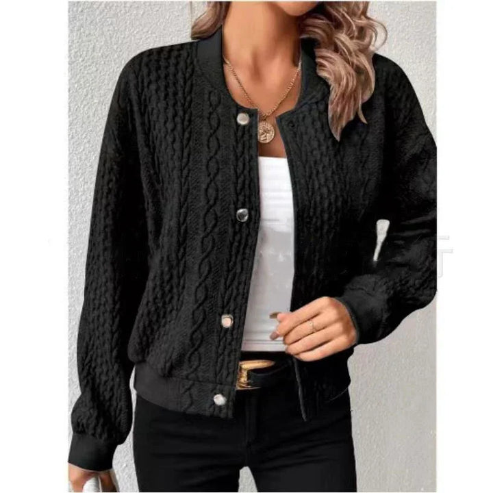 Woman wearing black cable knit button-up cardigan over white top with black pants and gold pendant necklace