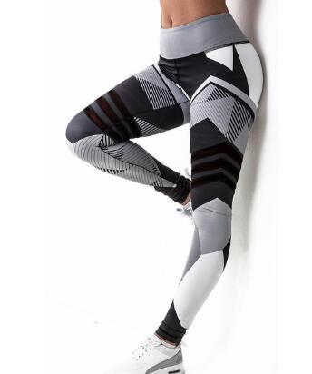 Woman wearing high-waisted geometric print black, white, and grey leggings and white sneakers