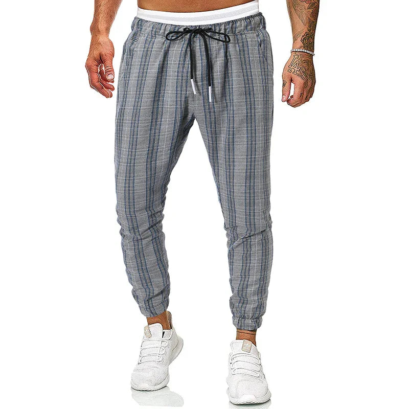 Men's grey plaid jogger pants with black drawstring and white sneakers on model
