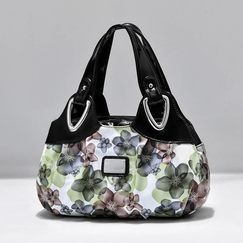 Stylish handbag with black leather handles and multicolor floral fabric body against gray background