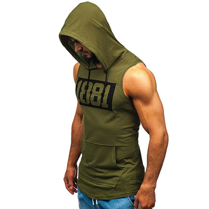 Muscular man wearing sleeveless olive green hoodie with hood up and 1881 print, paired with blue jeans