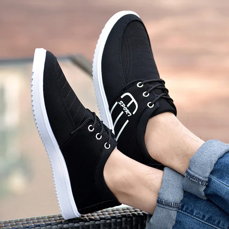 Black casual sport shoes with white soles worn with rolled-up blue jeans outdoors