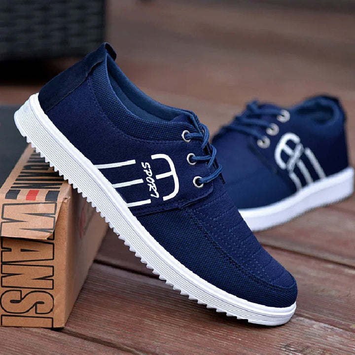 Navy blue casual sports shoes with white soles and laces, displayed on wooden floor and brown box