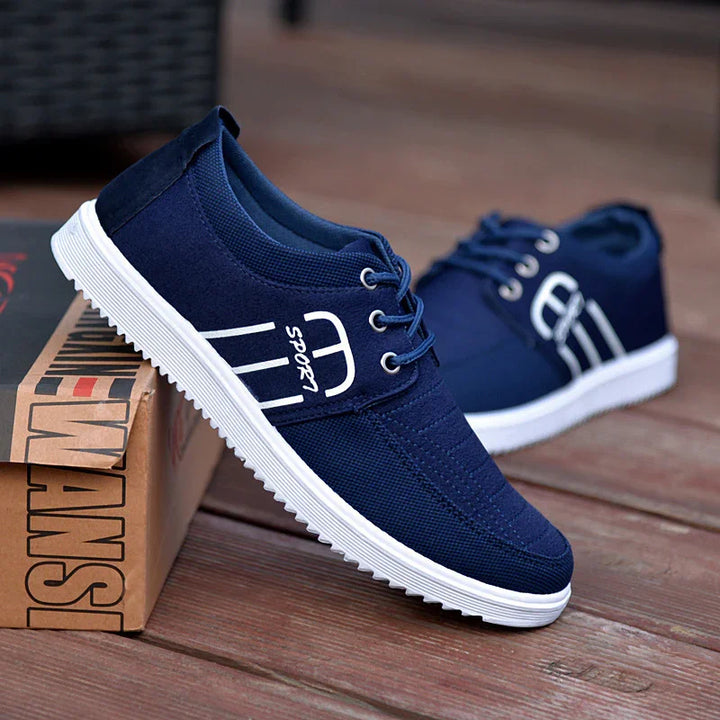 Blue casual lace-up men's shoes with white soles displayed on wooden floor and box