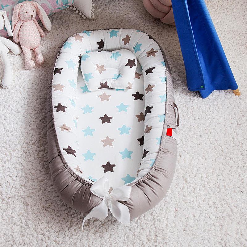 Baby nest with blue and brown stars print, white bow, pillow, and stuffed bunny on soft carpet