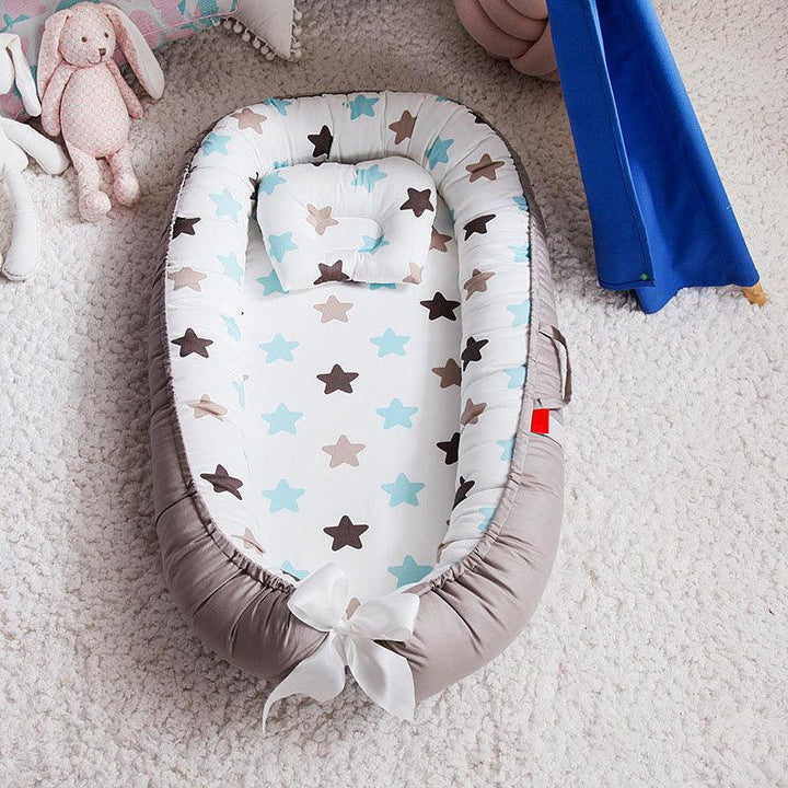 Baby nest with blue and brown stars print, white bow, pillow, and stuffed bunny on soft carpet
