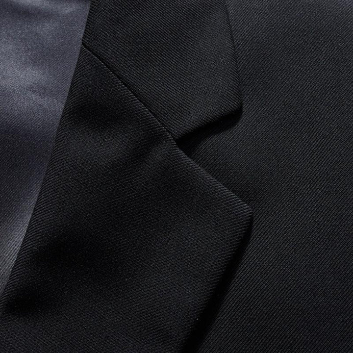 Close-up of black fabric suit jacket lapel with smooth satin background texture