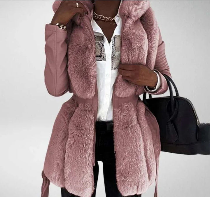 Woman wearing a pink faux fur coat over a white blouse, holding a black handbag