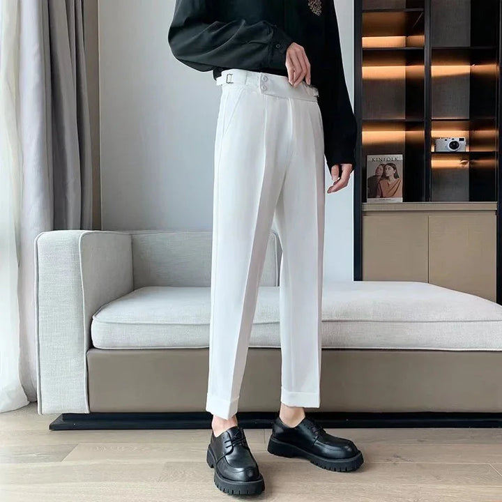 Person wearing white tailored pants and black leather shoes standing in modern living room