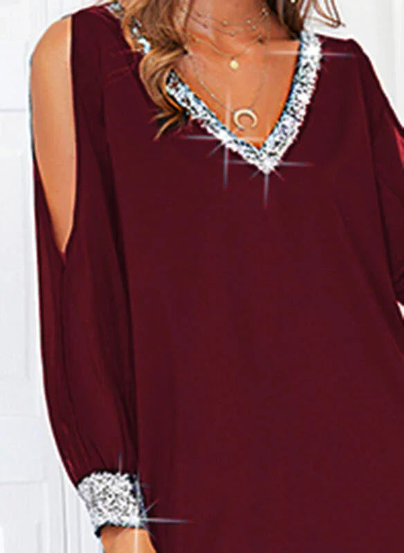 Woman wearing a burgundy cold-shoulder dress with silver sequin trim on neckline and cuffs