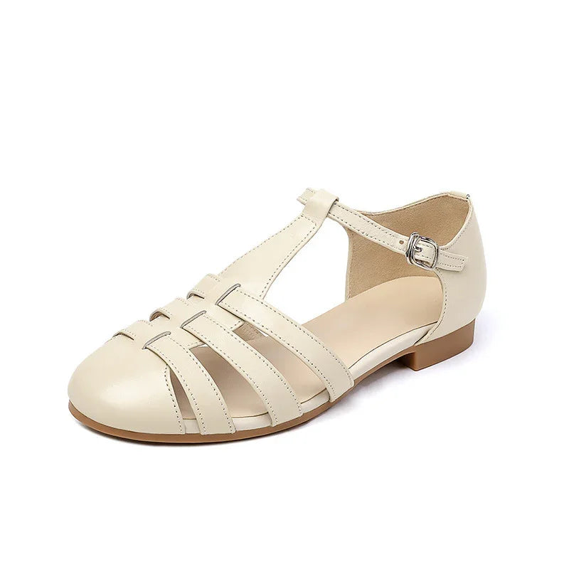 Beige women's T-strap flat sandal with buckle closure and cutout leather design