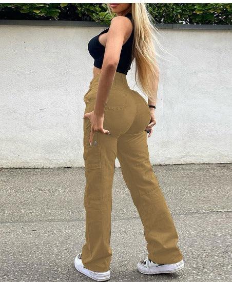 Woman wearing tan cargo pants and black crop top posing outdoors against a white wall